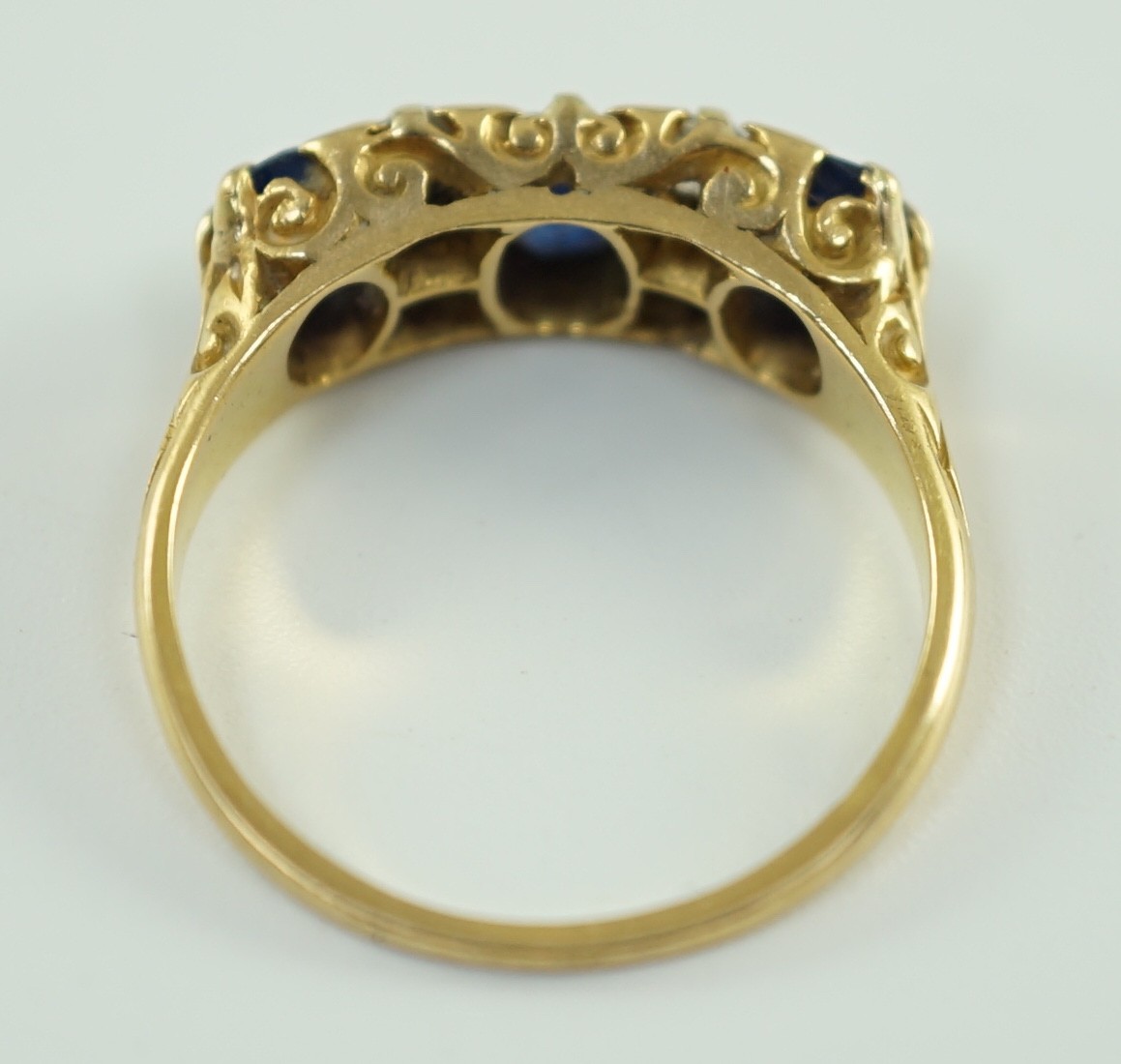 An early 20th century 18ct gold, three stone oval cut sapphire and four stone diamond spacer set half hoop ring